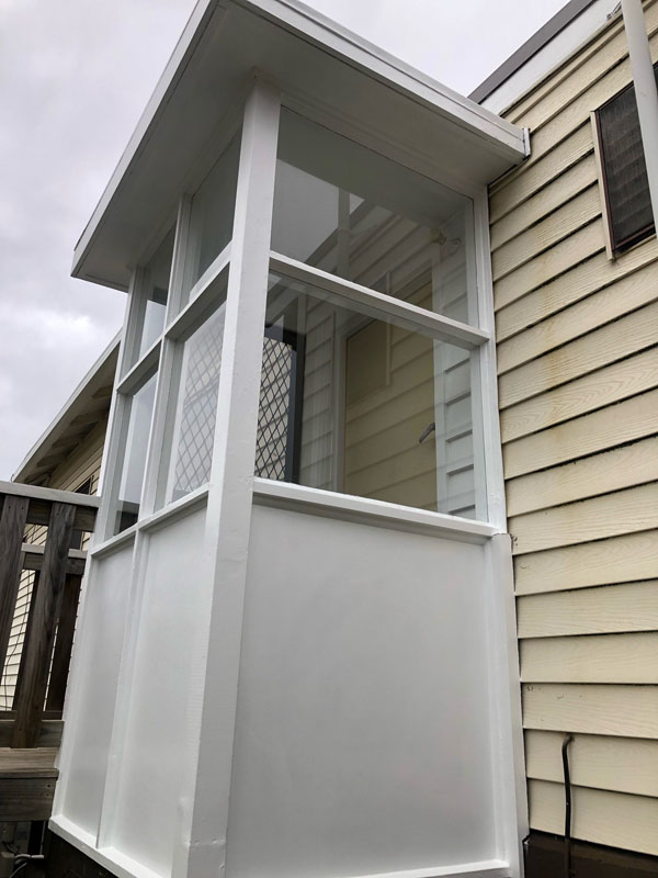 White enclosed entry porch with windows on the side of a weatherboard house