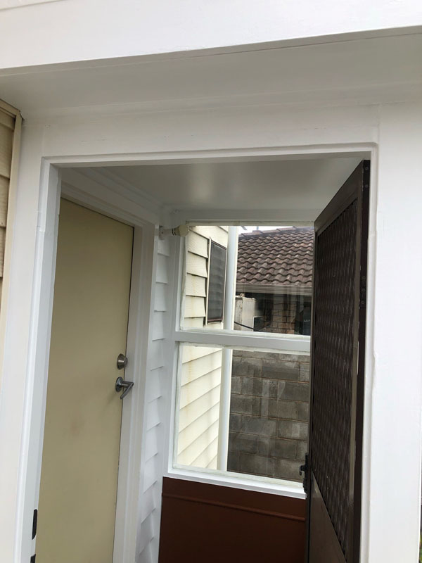 Enclosed entry porch with white framing, a window and a lattice screen door