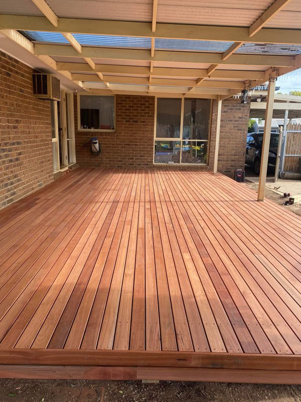 New hardwood deck under a pergola at the back of a brick house